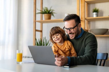 Evde dizüstü bilgisayar kullanan, video görüşmesinde sanal parti yapan, ekommerce ailesi ile online alışveriş yapan tatlı, heyecanlı, küçük çocuklu mutlu bekar ebeveyn.
