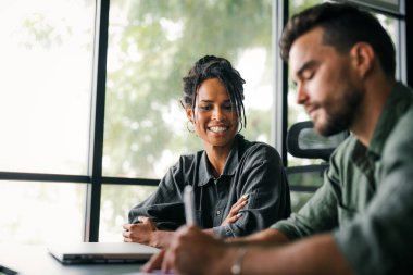 Neşeli çok ırklı meslektaşlar, ofis içi iş günlerinde başlangıç projesini tartışıyor ve gülümsüyor. Mutlu çeşitli başarılı iş arkadaşları yeni bir projede birlikte çalışıyorlar..