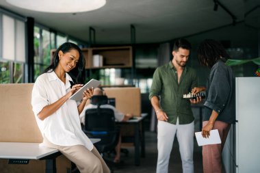 Tablet teknolojisi kullanarak çalışan iki iş adamından oluşan idari ekip şirket ofisinde yürüyor. Mutlu profesyonel gülümseyen işadamı ve iş kadını iş yerinde sohbet ediyorlar.