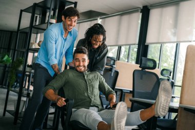 Bin yıllık çok ırklı takım insanlar eğlenmek oda ofis, heyecanlı farklı çalışanlar iş kopma komik faaliyet zevk gülüyor koltuklarda sürme yaratıcı samimi işçiler birlikte oyun oynamak