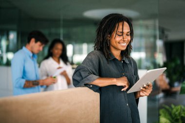 Gülümseyen Afro-Amerikan başarılı iş kadını, serbest çalışan, iş arkadaşı iş yerinde dijital cihaz kullanan kadın lider.