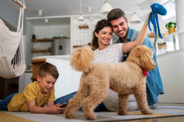 Mutlu bir aile oyunu, evde köpekle eğlenmek. Portre anne, baba ve çocuk oturma odasında kaliteli zaman, sevgi ve bakım için birlikte hafta sonu