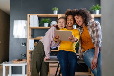 Bir grup genç kız arkadaş alet kullanıyor, konuşuyor ve birlikte gülümsüyorlar. İnsan teknolojisi kavramı.