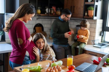 Mutlu aile hafta sonu kahvaltısı sırasında mutfakta eğleniyor. Hamile anne, heyecanlı kızıyla hamileliğinin son üç ayının tadını çıkarıyor..