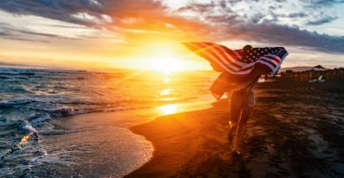 Mutlu kadın gülümseyip plajda koşarken bağımsızlık gününü kutluyor ve Amerika 'da özgürlüğün tadını çıkarıyor.