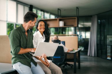 Mixed team of software engineers brainstorming ideas for new code library in front of computer screens compiling algorithms. Diverse app developers collaborating on group project in it agency office.