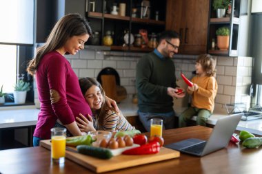 Mutlu kız, hamile annesinin karnına sarılıyor. Hamile bir kadını kucaklarken bebek hareketlerini dinleyen heyecanlı kız.