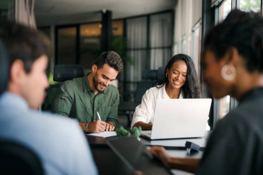 Neşeli çok ırklı meslektaşlar, ofis içi iş günlerinde başlangıç projesini tartışıyor ve gülümsüyor. Mutlu çeşitli başarılı iş arkadaşları yeni bir projede birlikte çalışıyorlar..