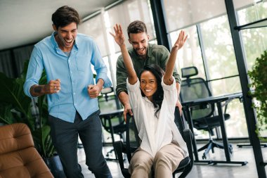 Bin yıllık çok ırklı takım insanlar eğlenmek oda ofis, heyecanlı farklı çalışanlar iş kopma komik faaliyet zevk gülüyor koltuklarda sürme yaratıcı samimi işçiler birlikte oyun oynamak