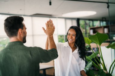 Neşeli, çeşitli, çok ırklı iş arkadaşları iş arasında eğleniyor teknolojiyi kullanıyor, birlikte çalışmaktan keyif alıyor, iş yerinde boş zamanlarında gülen arkadaşlar.