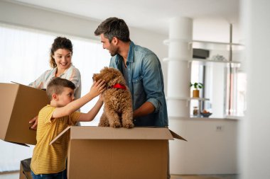Taşındığı gün yeni evde karton kutuları olan mutlu bir aile. İpotek, aile ve gayrimenkul konsepti, mutlu anne, baba ve çocuk kutuları yeni eve taşınıyor.