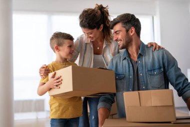 Yeni bir apartmanda kutularla taşınan çocuklu mutlu bir aile. Ev sahibi, taşınma günü için heyecanlı aile, taşınma ve kiralama konsepti