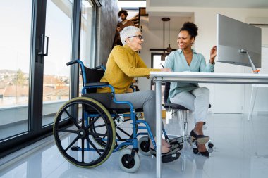 Modern bir çalışma alanında işbirliği yapan, çizelgeleri analiz eden ve birlikte çalışan çok ırklı iş arkadaşları, takım çalışmalarını, çeşitliliği ve dahil edilmeyi gösteriyor