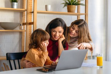 Evde dizüstü bilgisayar kullanan, video görüşmesinde sanal parti yapan, internetten aile alışverişi yapan, tatlı, heyecanlı çocukları olan mutlu bekar bir ebeveyn.