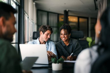 Ofisteki dijital cihazları kullanarak gülümseyen bir yönetici ekibi. Çeşitli profesyonel liderler yöneticiler ve çalışanlar takım çalışmasında çalışan dijital finans projesini tartışıyor.