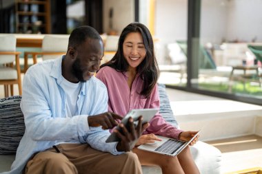 Dijital yaşam tarzı ve çevrimiçi bağlantı. Modern teknoloji odaklı dünyada eğlence, alışveriş ve kusursuz iletişimin tadını çıkaran çok ırklı mutlu bir çift.