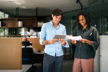 İki farklı etnik çeşitlilikte mutlu iş adamı şirket ofisinde dizüstü bilgisayar kullanarak konuşuyorlar. İş yerindeki meşgul iş adamları ve kadın meslektaşları.