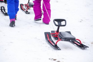 Bakuriani, Georgia 'daki kış parkındaki karlı tepede kızakla tırmanan insanlar.