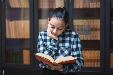 güzel kız öğrenci kütüphanede oturan ve bir kitap okuma, eğitim