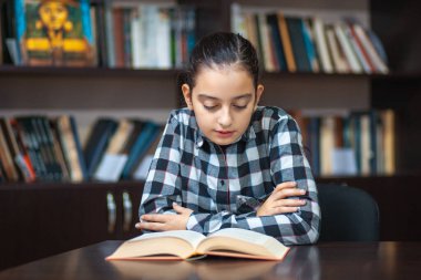 güzel kız öğrenci kütüphanede oturan ve bir kitap okuma, eğitim