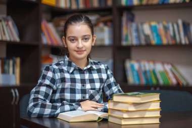 güzel kız öğrenci kütüphanede oturan ve bir kitap okuma, eğitim