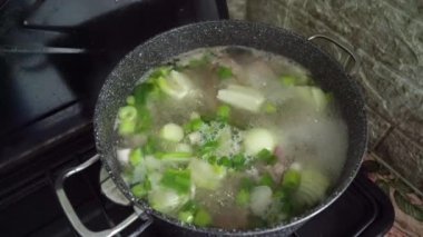 Tencerede otlu et suyu çorbası pişirmek. Yiyecek.