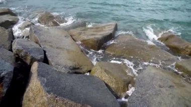 Deniz suyu sahilde taş yıkıyor. Dalgalar kaya uçurumunu kırıyor. Doğa