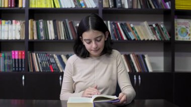 Kütüphanede kitap okuyan ergen kız. Eğitim. Yavaş çekim