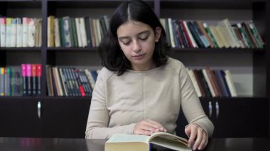 Kütüphanede kitap okuyan ergen kız. Eğitim. Yavaş çekim
