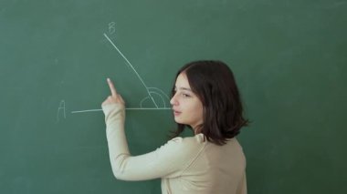 Genç bir kız matematik dersi sırasında tahtadaki matematik problemini çözer. Eğitim. Yavaş çekim