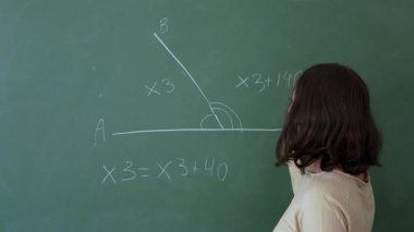 Genç bir kız matematik dersi sırasında tahtadaki matematik problemini çözer. Eğitim. Yavaş çekim