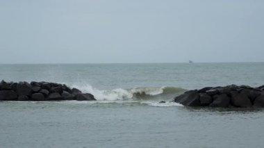 Dalgalar deniz kıyısındaki kayalara çarpıyor, deniz manzarası, Fiumichino plajı. Yavaş çekim