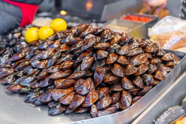 Mağazada bir sürü kırmızı midye satılıyor. Deniz ürünleri.