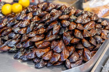 Mağazada bir sürü kırmızı midye satılıyor. Deniz ürünleri.