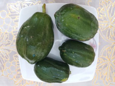 Masadaki beyaz tencerede yeşil papayalar