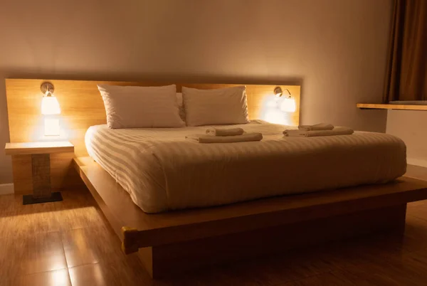 pillows and blanket in bed with light from lamps in modern bedroom at night