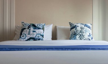 Mavi yastıklar ve battaniye beyaz yatak odasında, deniz kıyısında. 