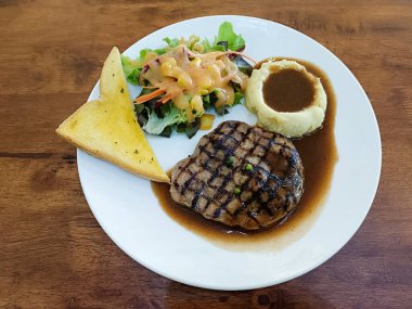 Lokantada beyaz tabakta siyah biberli domuz bifteği.