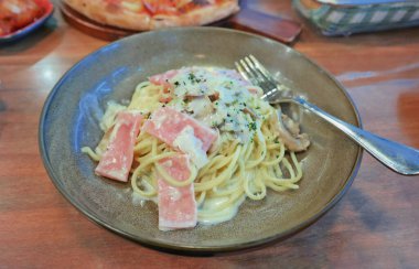 Lokantada seramik tabakta mantarlı jambon ve jambonlu spagetti.