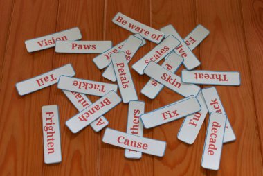 Sınıftaki kahverengi ahşap masanın üstündeki kelime kartlarının üst görüntüsü.