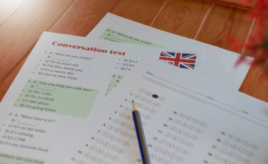 English conversation test and bubble answer sheet on table in classroom clipart