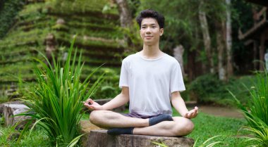 Huzurlu bir adam meditasyon yapıyor ve güzel bir günde dışarıda poz veriyor. Yoga, pilates, spor, sağlıklı yaşam tarzı konsepti.