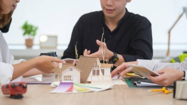 Modern kurumsal ofiste inşaat planları üzerinde çalışan mimarlardan oluşan bir ekip..