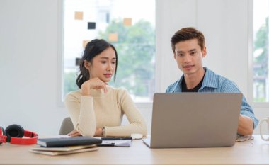 İki genç iş adamı bilgisayar ekranında online projeyi tartışıyorlar. İş ve takım çalışması kavramı.