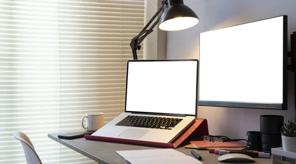 现代工作场所的黑桌上有白色的空白电脑屏幕 笔记本电脑和用品 — 图库照片