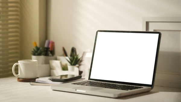 笔记本电脑 白色桌子上有空显示屏 咖啡杯 相框和文具 — 图库照片
