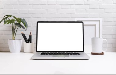 Laptop bilgisayarı, kahve fincanı ve beyaz masada saksı bitkisi. Reklam tasarımınız için boş ekran.