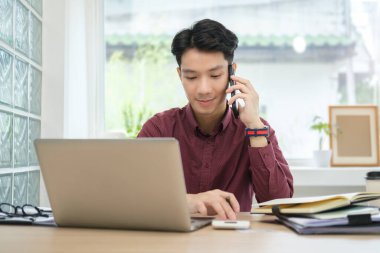 Yakışıklı bir çalışan müşteriyle hoş sohbetler yapıyor ve dizüstü bilgisayarını ahşap masada kullanıyor..