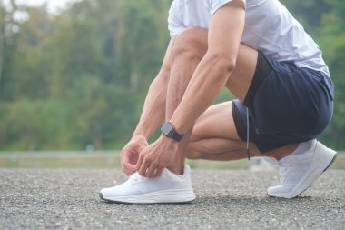 Sporty asian male tying shoelace, prepare exercise in the morning.	