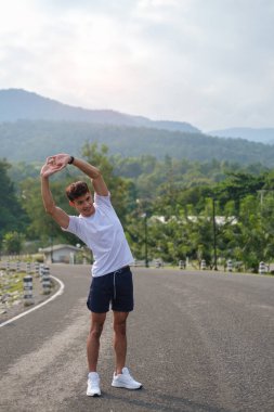 Yakışıklı genç atletik adam sabah egzersizden önce ısınıyor. Sağlıklı yaşam tarzı kavramı.